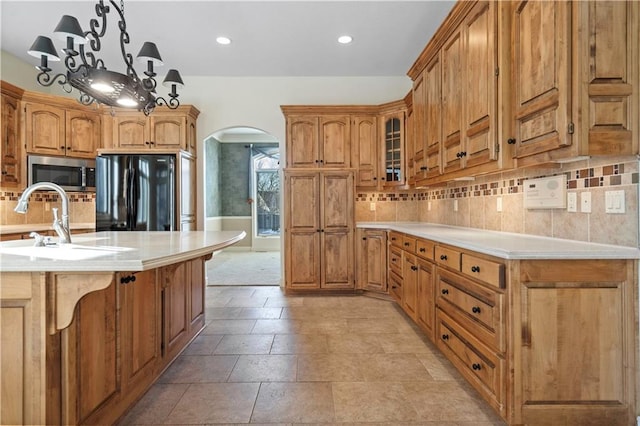 4704 W 152nd St, Leawood, KS 66224 - kitchen with freestanding refrigerator, stainless steel microwave, arched walkways, light countertops, and tasteful backsplash