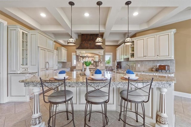 21211 E 34th St S, Independence, MO 64057 - kitchen with a large island, coffered ceiling, backsplash, a kitchen bar, and light stone counters