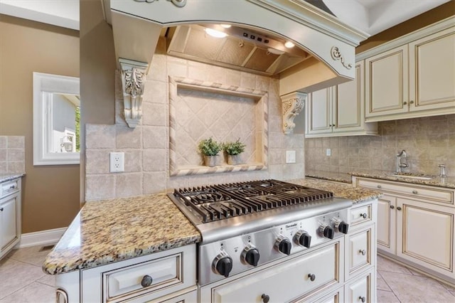 21211 E 34th St S, Independence, MO 64057 - kitchen featuring cream cabinets, stainless steel gas stovetop, tasteful backsplash, light tile patterned floors, and a sink