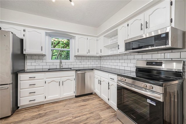 1917 N Concord Rd, Independence, MO 64058 - kitchen with appliances with stainless steel finishes, dark countertops, a textured ceiling, and white cabinetry
