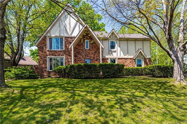 tudor home featuring stucco siding, a front yard, and brick siding