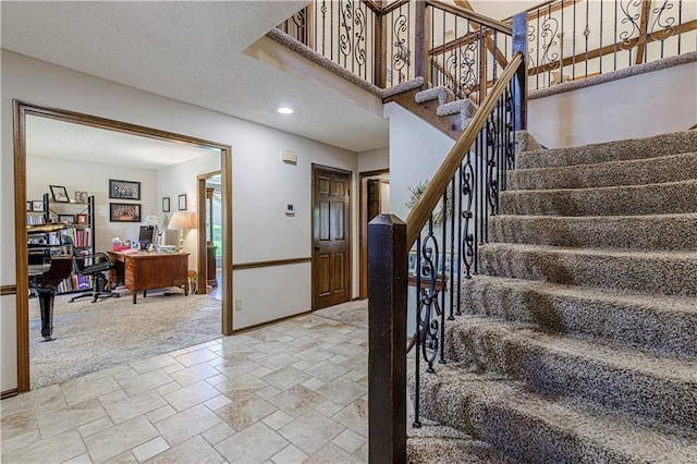 stairway with baseboards, stone finish flooring, and carpet