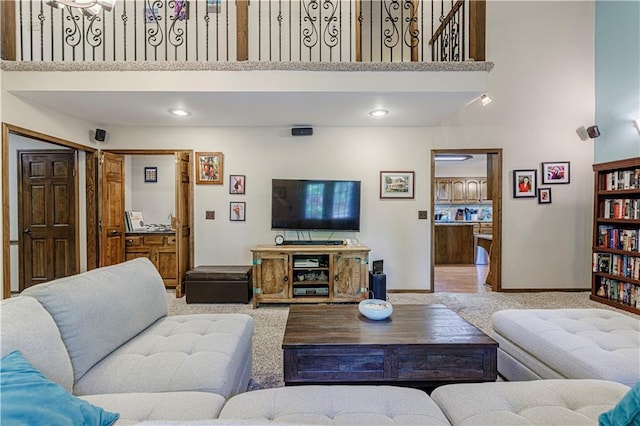 carpeted living area featuring a towering ceiling and baseboards