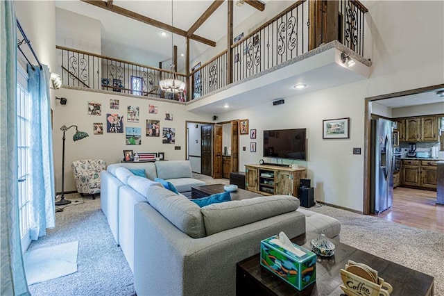 living room with a towering ceiling, light colored carpet, baseboards, a chandelier, and recessed lighting