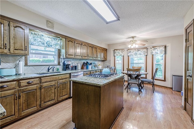 kitchen with a sink, stainless steel appliances, tasteful backsplash, a kitchen island, and healthy amount of natural light