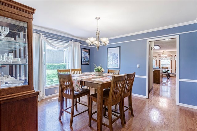 dining room with baseboards, a chandelier, ornamental molding, and wood finished floors