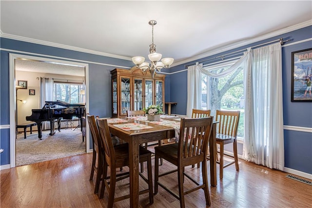 dining room featuring a chandelier, ornamental molding, baseboards, and wood finished floors