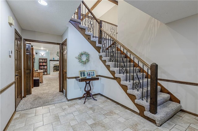 stairs with stone finish floors, baseboards, carpet, and a fireplace