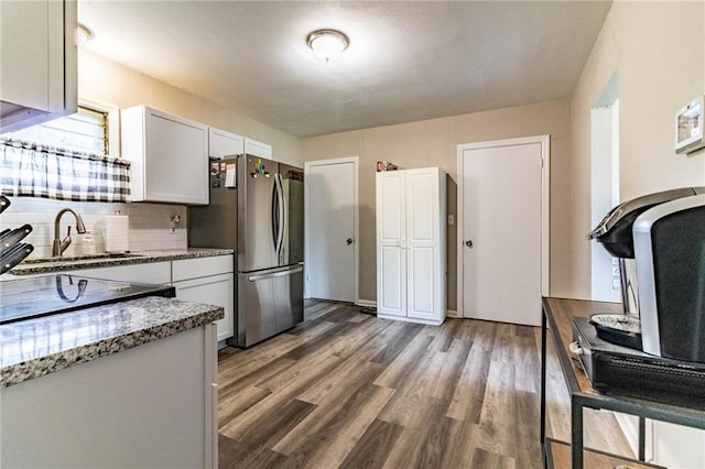 1007 Vest Dr, Warrensburg, MO 64093 - kitchen featuring freestanding refrigerator, a sink, light stone countertops, wood finished floors, and white cabinetry