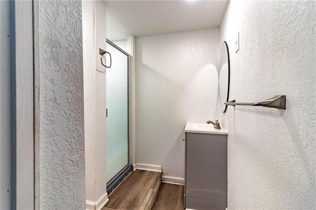 1007 Vest Dr, Warrensburg, MO 64093 - full bathroom featuring wood finished floors, vanity, a shower stall, a textured wall, and baseboards