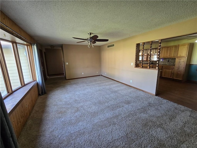 empty room with a ceiling fan, dark colored carpet, a textured ceiling, and baseboards