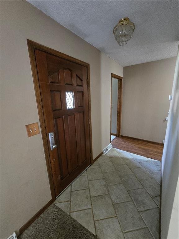 foyer with a textured ceiling and baseboards