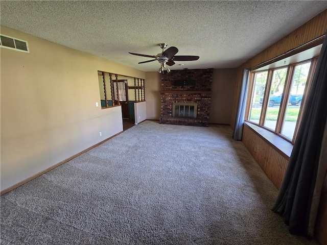 unfurnished living room featuring ceiling fan, carpet floors, a brick fireplace, a textured ceiling, and baseboards