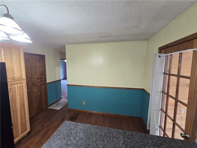 empty room with wood finished floors, a textured ceiling, and baseboards