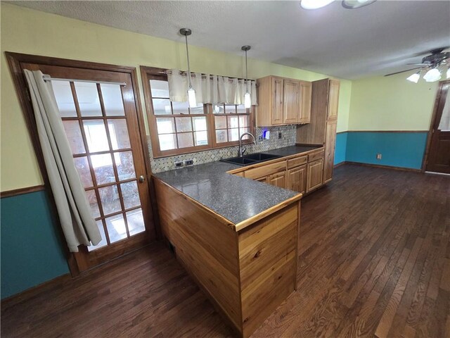 kitchen with a sink, dark countertops, dark wood finished floors, and baseboards