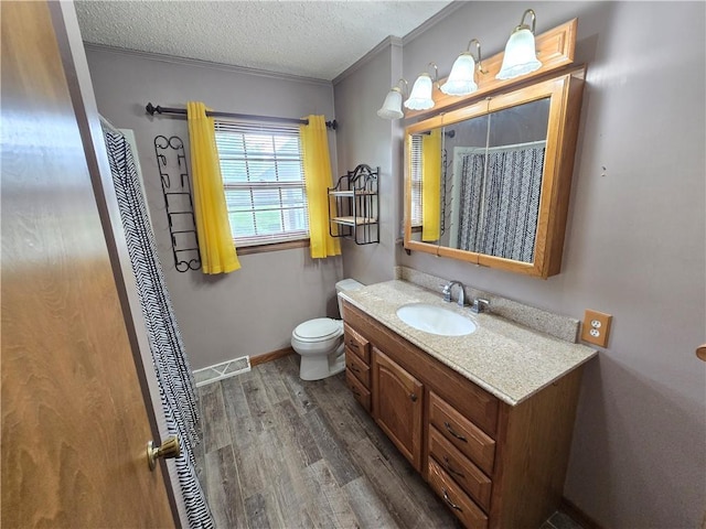 bathroom with wood finished floors, crown molding, vanity, toilet, and a textured ceiling