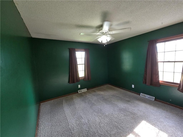 carpeted empty room with ceiling fan, a textured ceiling, and baseboards