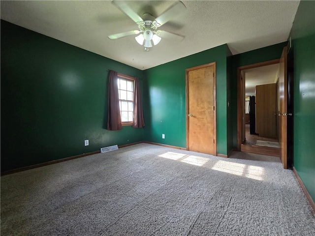 unfurnished bedroom with carpet flooring, baseboards, ceiling fan, and a textured ceiling