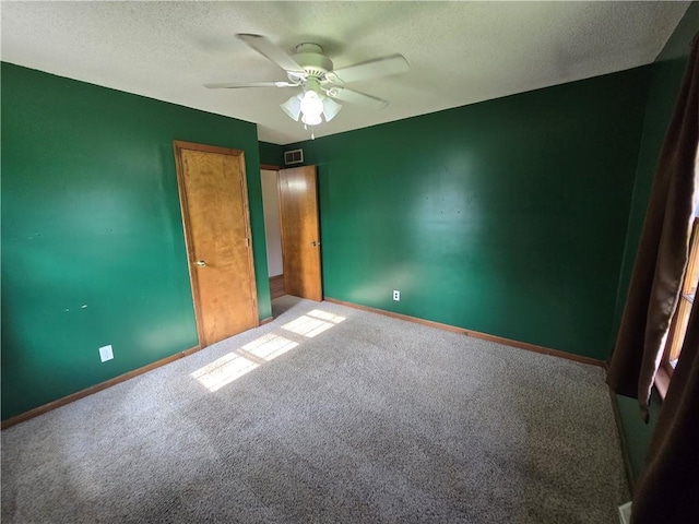 unfurnished bedroom featuring carpet floors, a textured ceiling, baseboards, and a ceiling fan
