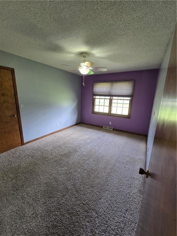 empty room with carpet, a ceiling fan, a textured ceiling, and baseboards