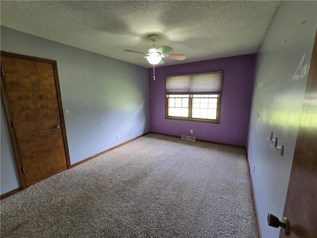unfurnished room featuring a ceiling fan, carpet, a textured ceiling, and baseboards