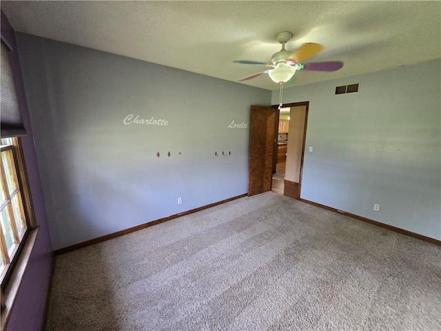 carpeted spare room featuring a ceiling fan, baseboards, and a textured ceiling