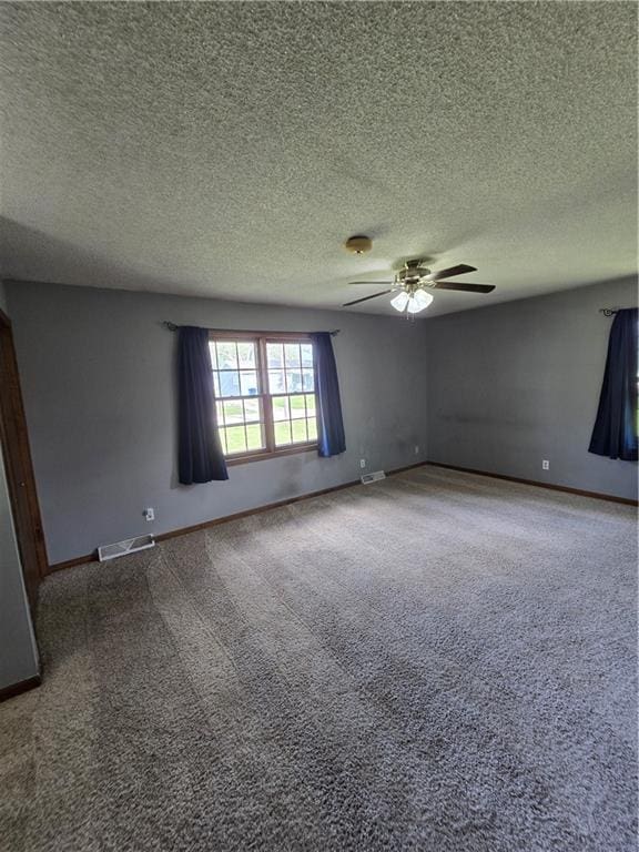 carpeted empty room with ceiling fan, a textured ceiling, and baseboards