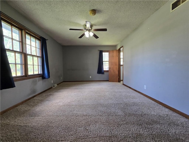 carpeted spare room with a textured ceiling, ceiling fan, and baseboards