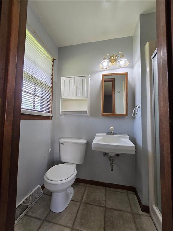 full bath with a sink, a stall shower, toilet, and baseboards