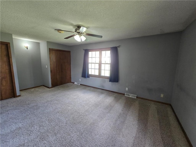 spare room featuring ceiling fan, a textured ceiling, carpet flooring, and baseboards