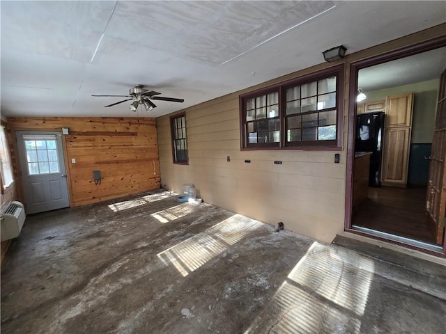 unfurnished living room featuring wood walls and ceiling fan