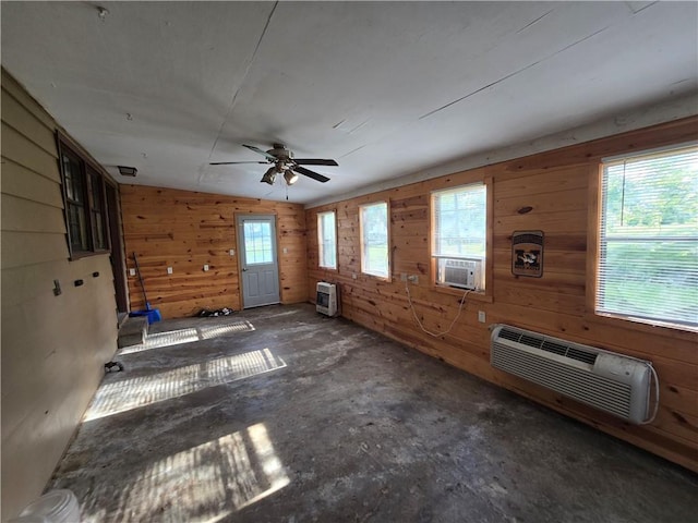 empty room featuring a wall mounted air conditioner, heating unit, wooden walls, ceiling fan, and cooling unit
