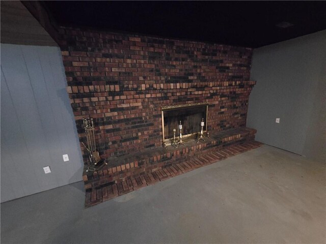 unfurnished living room with concrete floors and a brick fireplace