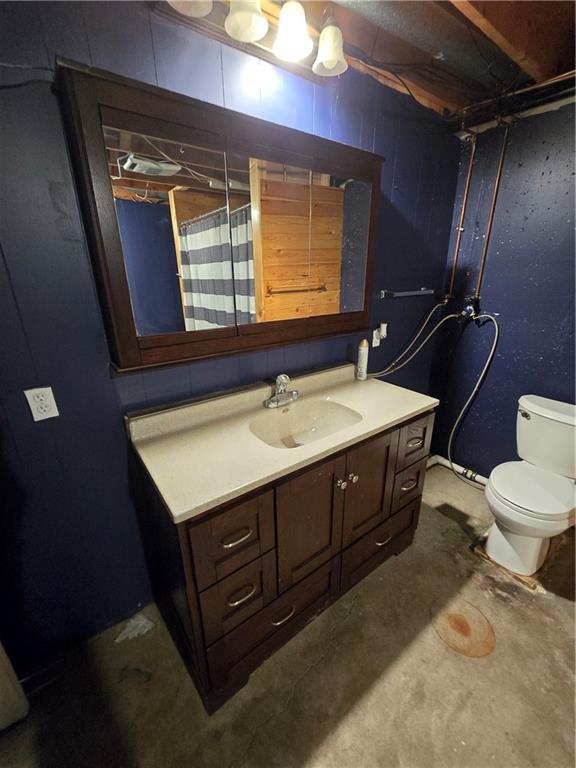 bathroom featuring toilet, vanity, and unfinished concrete floors