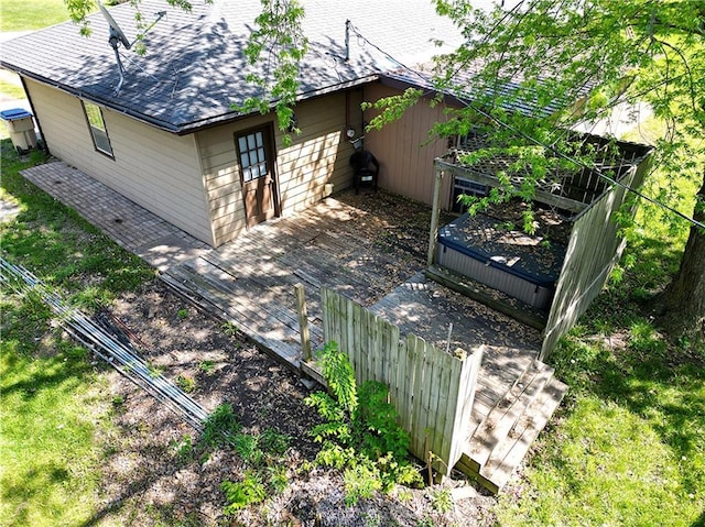 back of property featuring a deck, fence, and roof with shingles