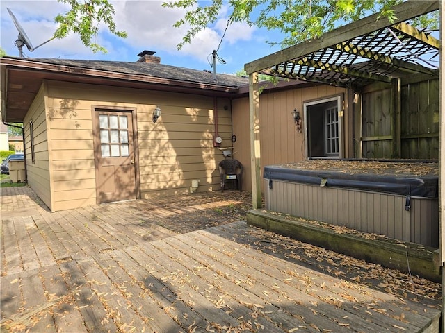 back of property with a hot tub, a deck, and a chimney