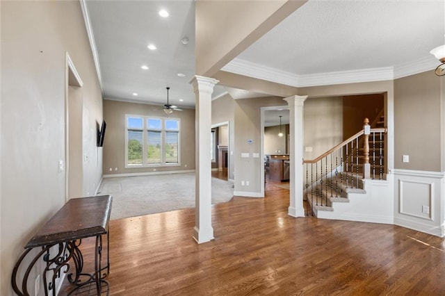 entrance foyer featuring ornate columns, crown molding, stairway, a ceiling fan, and wood finished floors