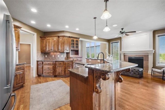 kitchen with stainless steel appliances, a kitchen breakfast bar, brown cabinets, a ceiling fan, and light wood-style floors