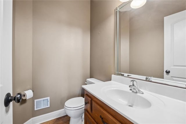 bathroom with toilet, vanity, baseboards, and wood finished floors