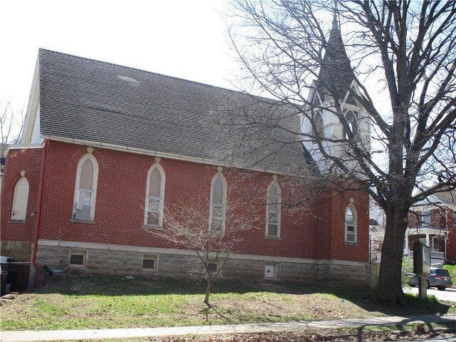 220 N 9th St, Atchison, KS 66002 - view of side of property with brick siding, a shingled roof, and a lawn