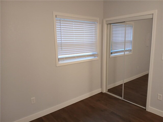 1029 Shearer Rd, Kansas City, KS 66103 - unfurnished bedroom with a closet, baseboards, dark wood-style flooring, and multiple windows