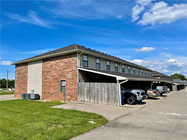 596 SE 105th Rd, Warrensburg, MO 64093 - view of side of home with brick siding, a yard, and covered parking