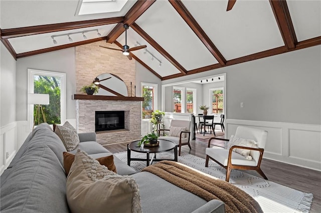 1036 NE Remington Ct, Lees Summit, MO 64086 - living room with a ceiling fan, wood finished floors, wainscoting, a decorative wall, and a stone fireplace