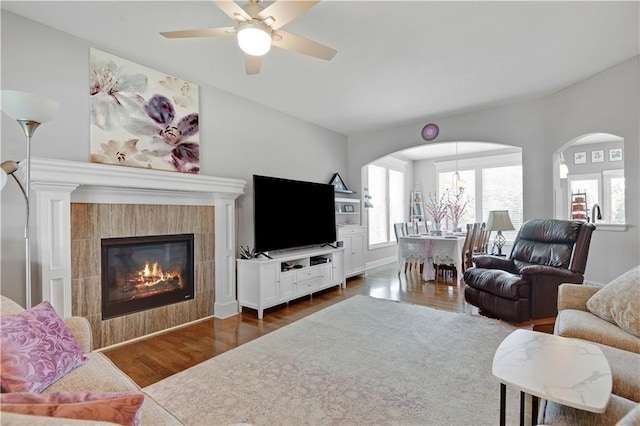 25201 W 149th Ter, Olathe, KS 66061 - living area featuring arched walkways, dark wood finished floors, a ceiling fan, and a tile fireplace