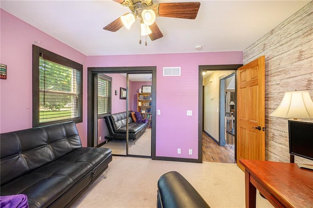 7277 SW Karen Rd, Trimble, MO 64492 - living area with light carpet, an accent wall, a ceiling fan, and wood walls