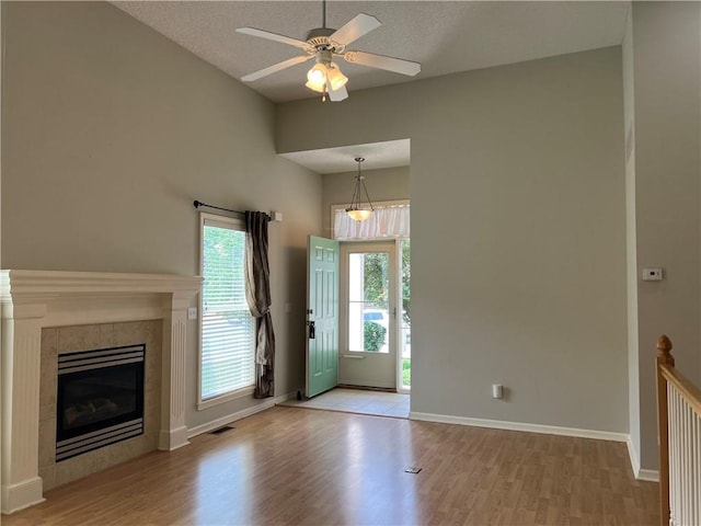 2017 S 137th St, Bonner Springs, KS 66012 - entrance foyer featuring light wood-style floors, a ceiling fan, baseboards, a tiled fireplace, and a textured ceiling