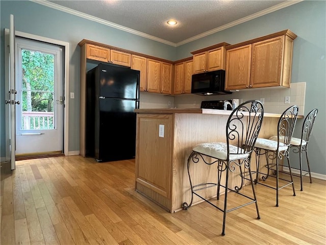 2017 S 137th St, Bonner Springs, KS 66012 - kitchen featuring black appliances, a peninsula, light wood-type flooring, crown molding, and baseboards