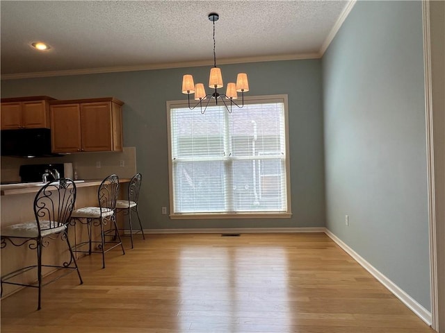 2017 S 137th St, Bonner Springs, KS 66012 - dining area featuring a chandelier, a textured ceiling, light wood-style floors, crown molding, and baseboards