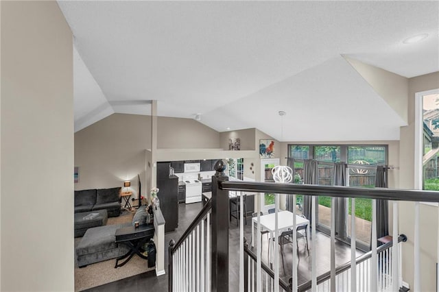 corridor with an upstairs landing and lofted ceiling