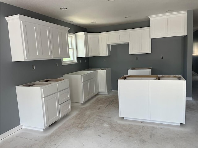 449 E Market St, Warrensburg, MO 64093 - kitchen featuring concrete floors, white cabinets, and a center island